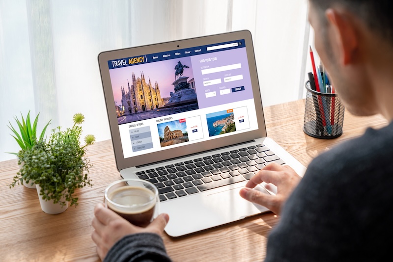 Man som sitter vid laptop och tittar på en resesajt